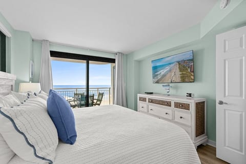 Relaxing oceanfront bedroom with king bed, smart TV, and sliding doors leading to the private balcony.