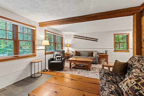 A cozy gathering space filled with natural light and views of the surrounding woods.