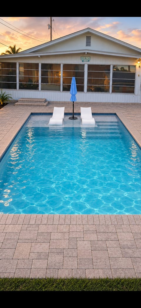 Sunset pool retreat with in-water loungers and screened patio