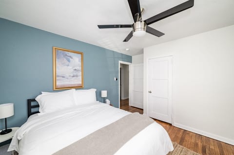 Queen bed with extra pillows and blankets, TV, workspace, and closet with hangers and shelving.