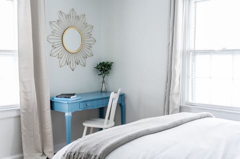 Queen bed with extra pillows and blankets, TV, workspace, and closet with hangers and shelving.