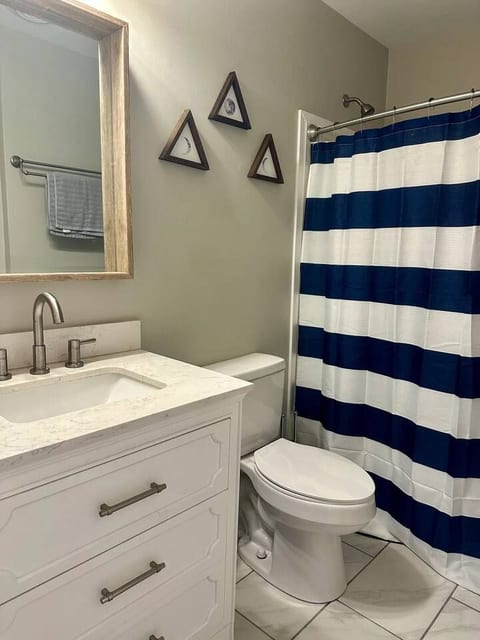 Renovated bathroom with bathtub, shower, single sink, closet and mirror.