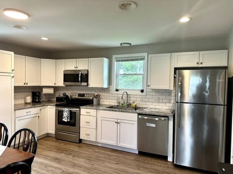 A fully equipped kitchen with stainless steel appliances, toaster, microwave, blender, and coffee maker.