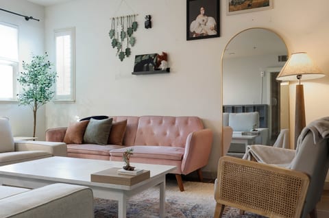 Bright, chic lounge with blush sofa, arched mirror, and airy natural light