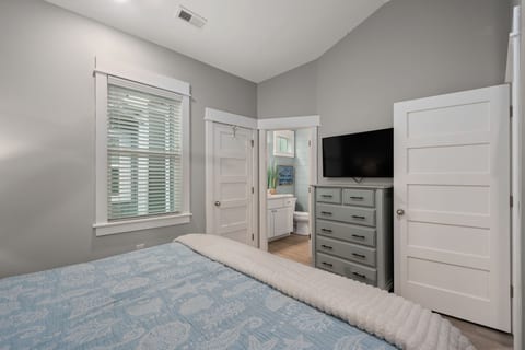 Bright bedroom with TV, tall ceilings, and ensuite bath access