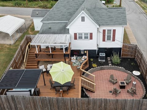 Private fenced backyard with covered deck dining, louvered pergola over hot tub, dining, game corner, cozy seating, firepit and propane heater