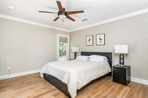 Bright, spacious bedroom with king bed, ceiling fan, and natural light