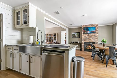 Open kitchen and dining area with farmhouse sink, fireplace, and TV