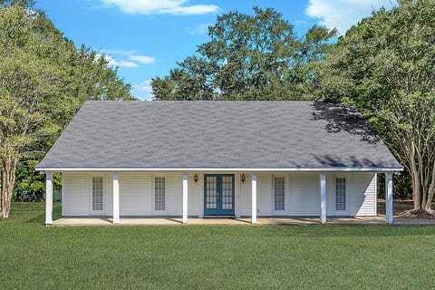 Charming cottage with covered porch, spacious lawn, and serene wooded setting
