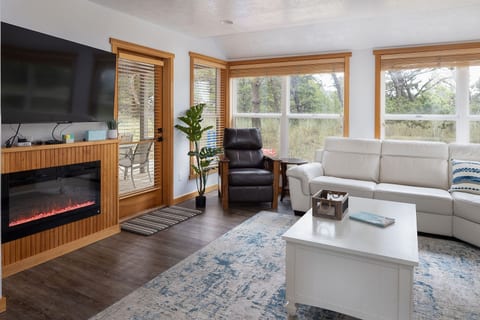 Living room with flat screen TV, NEX playground gaming system, and leather sectional with 4 reclining seats.