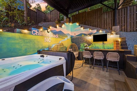 The downstairs outdoor area features a cozy bar, TV, a relaxing hot tub and a vibrant hand painted mural.