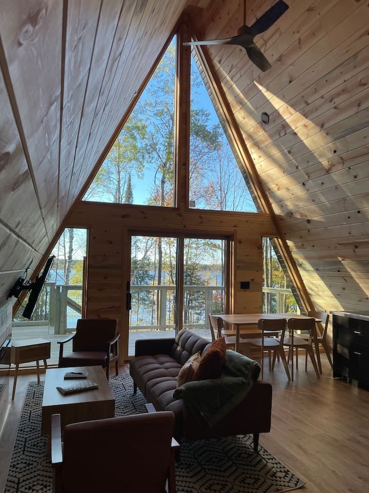 Sunlit A-frame living space with lake views and soaring wood ceilings