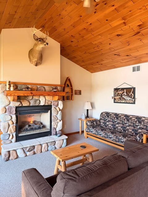 Cozy cabin living room with stone fireplace and warm wood ceilings
