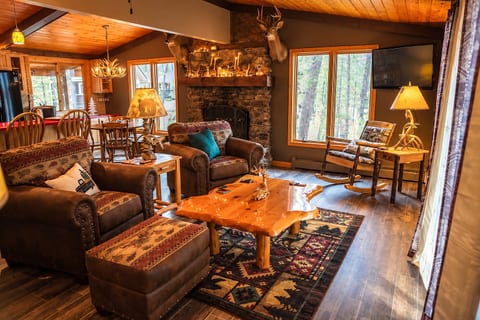 Cozy lodge living room with stone fireplace and peaceful forest views