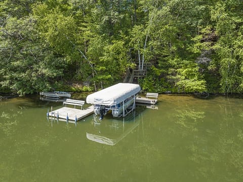 Private wooded lakefront dock with covered boat lift and serene water views
