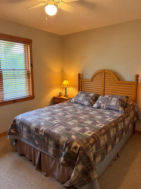 Cozy queen bedroom with warm lighting, ceiling fan, and natural light