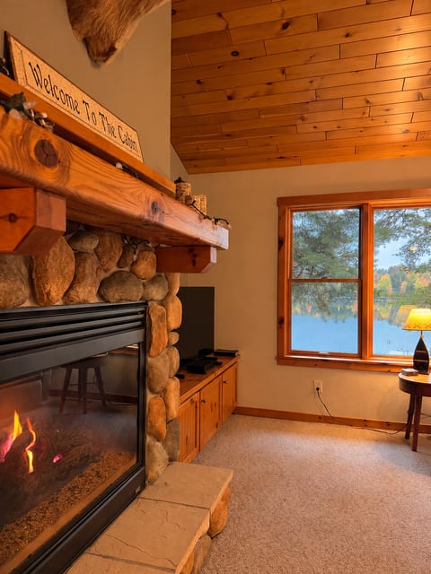 Cozy stone fireplace and serene lake views in a warm cabin-style lounge