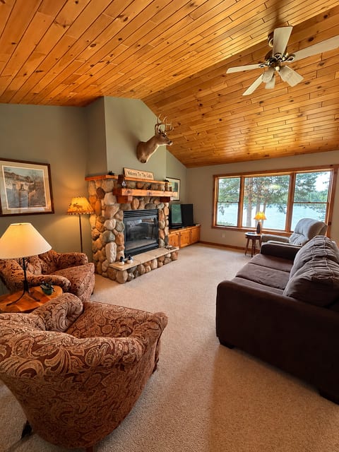 Cozy lakeview living room with stone fireplace and vaulted wood ceiling