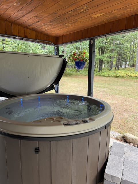 Covered hot tub patio with peaceful backyard and wooded views