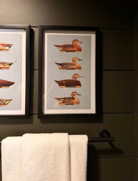 Moody bathroom styling with plush towels and charming framed duck artwork