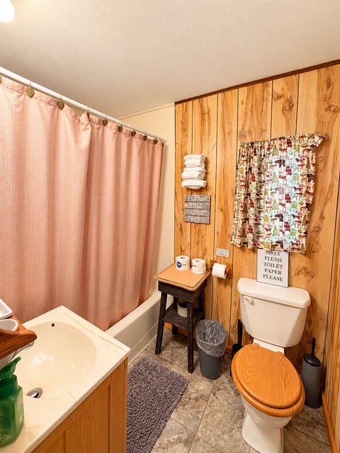Cozy rustic bathroom with full tub, warm wood accents, and guest essentials