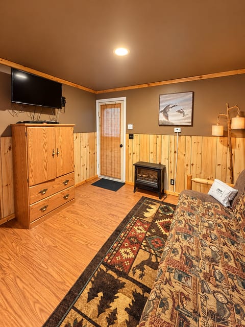 Cozy rustic lounge with futon, TV, and fireplace charm