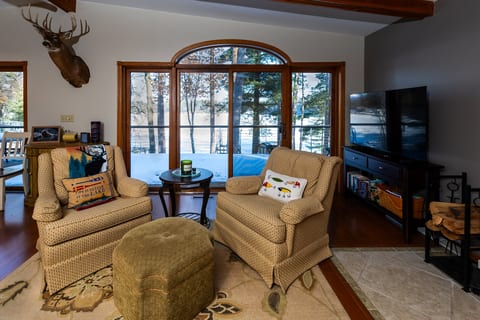 Cozy lakeview lounge with rustic charm, fireplace, and picture windows