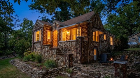 Cozy stone cottage with warm evening glow and inviting outdoor seating