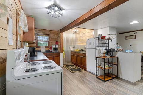 A rustic farmhouse kitchen with reclaimed plank walls, deep farmhouse sink, new wood cupboards , full stock of cooking supplies and spices, coffee bar, stove, microwave, refrigerator 