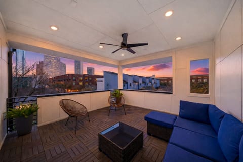 Large covered third-floor deck featuring an overhead fan, sectional seating, and skyline views of downtown Houston.