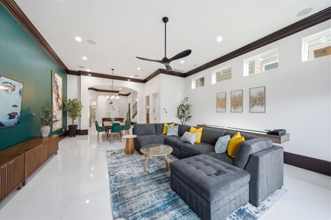 Gather beneath soaring ceilings in a professionally designed living space featuring an oversized sectional, shuffleboard, a 75-inch TV, and views out to your private backyard oasis.