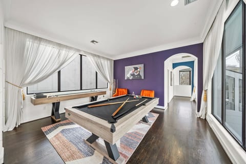 Unwind in the game room, featuring shuffleboard, pool table, & sitting area where spectators can relax & enjoy the action. Open to the dining room, it offers perfect blend of entertainment & relaxation, ideal for fun-filled nights w/friends & family.