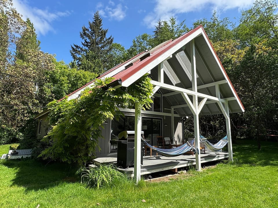 A bright sunny day at the Owl House in summer is hard to beat. This is a view to the main house and huge covered porch with hammocks and grill.