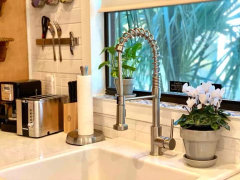 Going tiny doesn’t have to mean going without. This gorgeous kitchen features stunning natural white marble countertops and farmhouse sink!