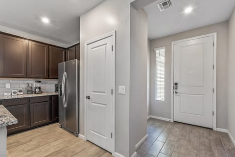 Bright entryway with modern kitchen, granite counters, and stainless appliances