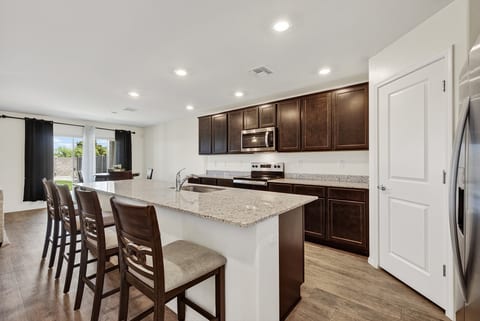 Spacious modern kitchen with granite island, bar seating, and backyard access