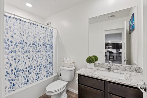 Bright modern bathroom with granite vanity and full tub-shower combo