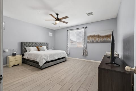 Spacious king bedroom with TV, ceiling fan, and bright modern style