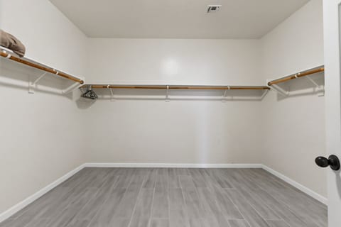 Spacious walk-in closet with ample hanging space and sleek tile floors