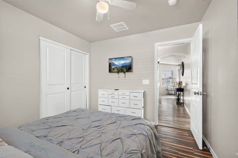 Bright, cozy bedroom with TV, dresser, and ample closet storage