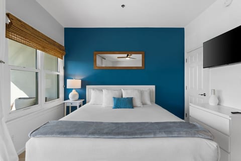 Bright modern bedroom with bold accent wall, TV, and natural light