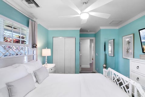 Guest bedroom with Queen bed, flat screen TV, ceiling fan, full length mirror and clothing storage