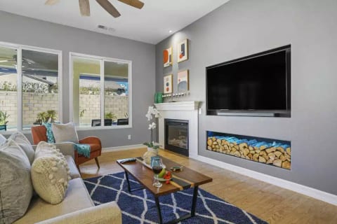 High ceilings, but cozy living room, with LG OLED SmartTV. Decorative-only firewood box and decorative fireplace. Sofa has been upgrade in 2026, and is larger than one pictured.