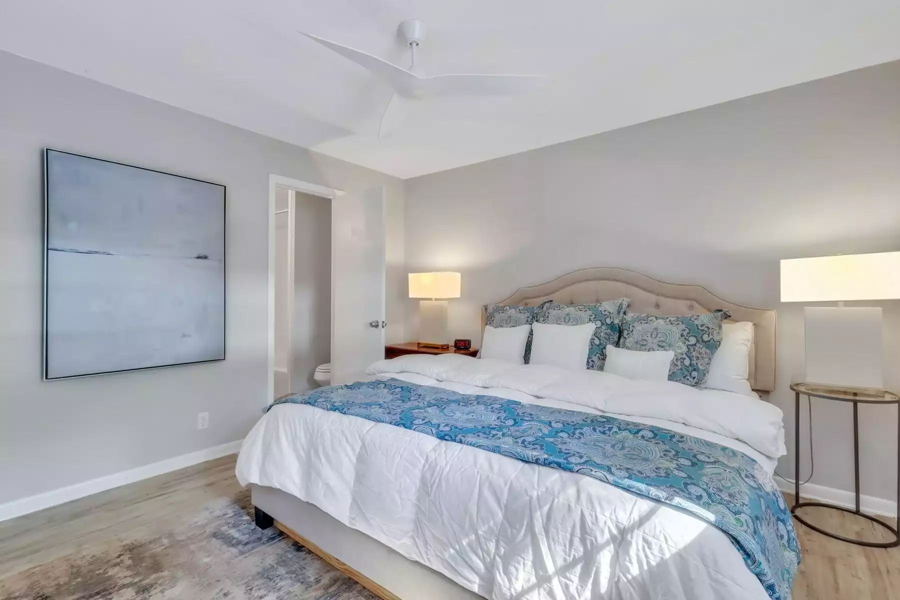 King size bed in the primary suite with a double vanity with tub and shower combo. King size bed in the primary suite with a double vanity with tub and shower combo. - The Cozy Cottage on St. Simons Island - St Simons Island