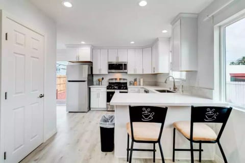 Kitchen with Full Fridge/Freezer, Range Stovetop w/ Oven, Dishwasher, Dining Counter, and Common Area Half-Bath