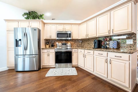 Chef’s kitchen stocked with stainless steel appliances and cooking essentials and coffee station.