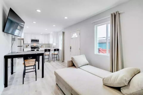 Open Concept Layout with Dining Table, Mounted 55" Roku TV, Sofa (Converts to Flat Bed), Blackout Curtains, Common Area Half-Bath, and Mini Split Air Conditioning (AC) System