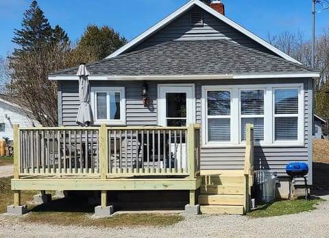 Deck on lake side with table, 4 chairs, umbrella, gas grill. There's also a charcoal grill and picnic table just below the deck.