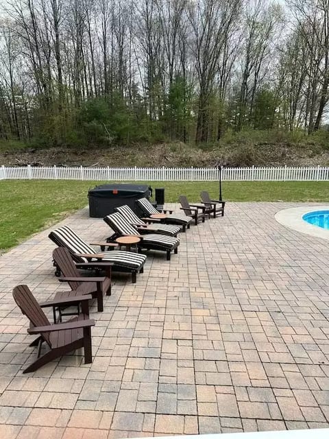 Beach lounge chairs and Adirondack chairs on beautiful pavers by in ground heated pool and hot tub