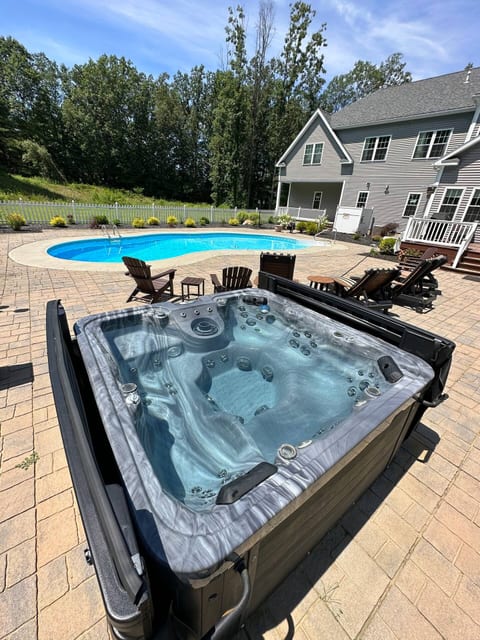 Updated hot tub and heated in-ground heated pool on back pavers in fenced in backyard